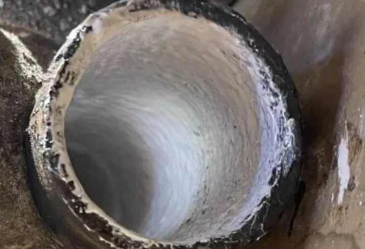 A view looking through the interior of a pipe that has been restored with a smooth white epoxy coating.
